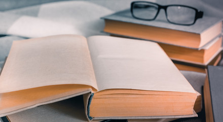 Stack of open vintage books with glasses