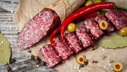 Italian salami with olives and spices on wooden background
