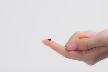 red drop of blood on the finger, female hand, blood test, unexpected cut, blood on a white...