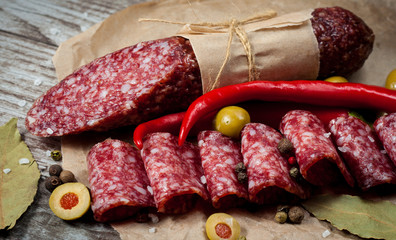 Italian salami with olives and spices on wooden background
