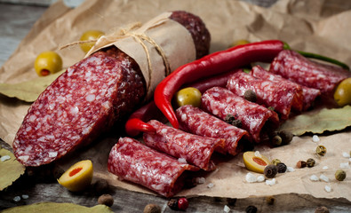 Italian salami with olives and spices on wooden background