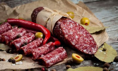 Italian salami with olives and spices on wooden background