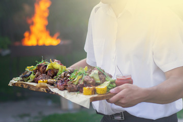 Waiter is offering grilled meat and vegetables