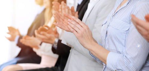 Business people clapping and applause at meeting or conference, close-up of hands. Group of unknown businessmen and women in modern white office. Success teamwork or corporate coaching concept