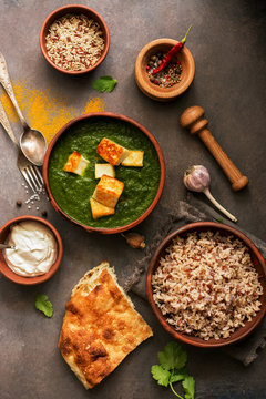 Indian food Palak Paneer , naan bread, rice and spices on a dark background. Top view, flat lay, copy space