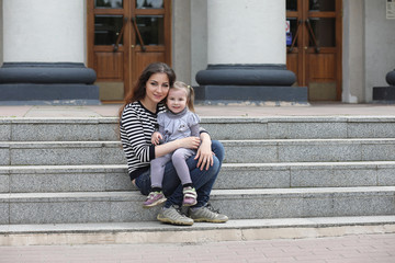 Children on a walk in the spring in the city park. The girl is walking in the park. Children and mom are walking around the city.