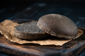 Fototapeta na wymiar Round black bun for the Burger in rustic style on a peper on a wooden Board