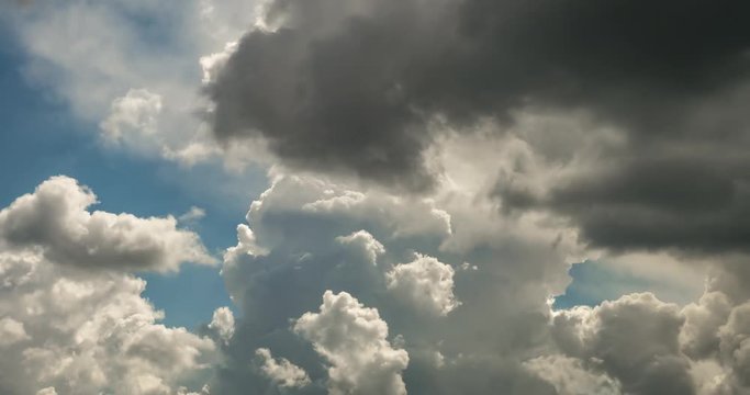 Time lapse clip of gray fluffy curly rolling clouds before storm in windy weather with sun rays