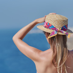 Attractive girl in bonnet hat and sunglasses relaxing on balcony against sea in summer.