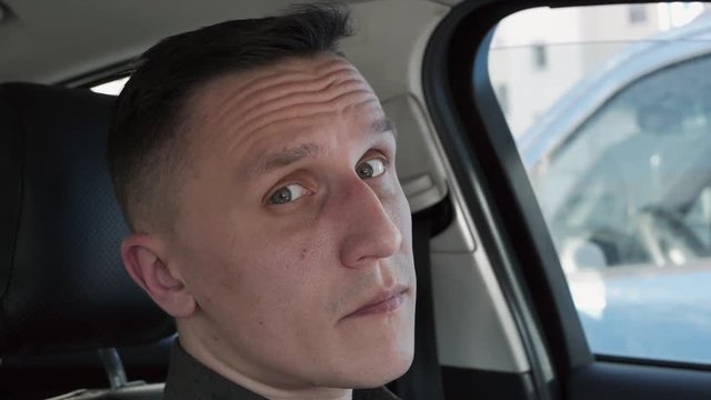 Portrait of a man sitting in a car. He shakes his head questioningly.