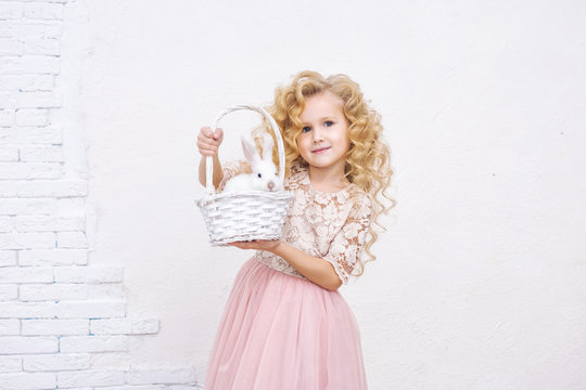 Little beautiful and cute child girl in a fashionable festive dress with animals rabbits in a white basket