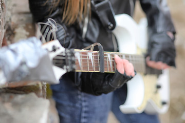 A rock musician girl in a leather jacket with a guitar