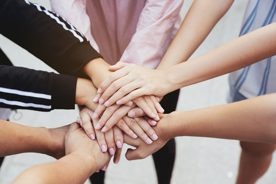 Close up at the hands many teenage girls. Show unity as a collaborative work together. To succeed, one has to understand each other in communication. Concept International Women's Day
