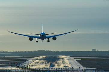 Airplane landing to airport in sunset