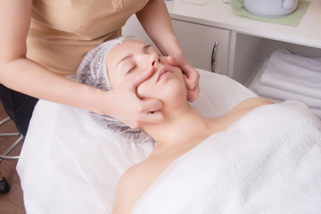 Closeup of young woman receiving face massage from massage therapist.