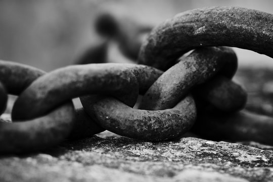 black and white image of a large chain lying on a stone
