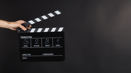 Fototapeta na wymiar Hand is holding Black Clapperboard or movie slate with write in number. it use in video production ,film, cinema industry on black background.