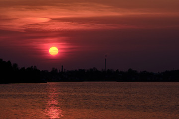 The sun goes down behind forest and industry