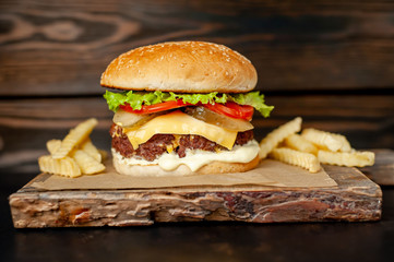 Delicious homemade hamburger with beef, salad, cheese, cucumber and french fries chalkboard on wood background