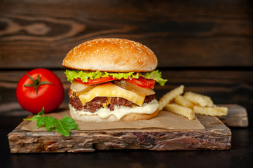 Delicious homemade hamburger with beef, salad, cheese, cucumber and french fries chalkboard on wood background