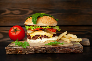 Delicious homemade hamburger with beef, salad, cheese, cucumber and french fries chalkboard on wood background