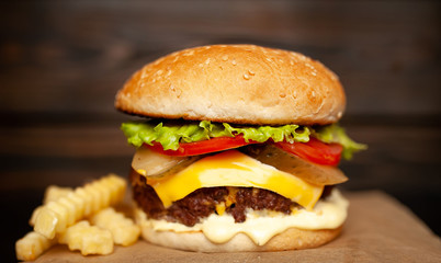  Delicious homemade hamburger made of beef, salad, cheese, cucumber and french fries on a wood background