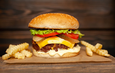  Delicious homemade hamburger made of beef, salad, cheese, cucumber and french fries on a wood background