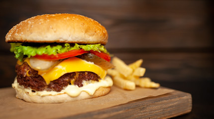  Delicious homemade hamburger made of beef, salad, cheese, cucumber and french fries on a wood background
