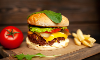  Delicious homemade hamburger made of beef, salad, cheese, cucumber and french fries on a wood background