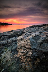 stone in the foreground and sea after sunset in the background