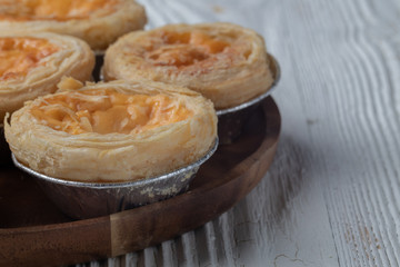 close up of egg tarts on wooden plate