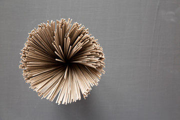 Uncooked buckwheat soba noodles in a glass jar over black background, overhead view. From above, top view. Copy space.