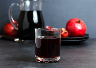 Pomegranate, pomegranate juice in a glass Cup. Dark background. Side view. The concept of therapeutic nutrition