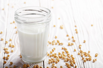 Non-dairy alternative Soy milk or yogurt in mason jar on white wooden table with soybeans aside