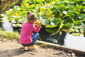 little girl playing in the park by the pond