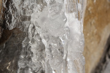 Icicles hanging on a ledge with rocky bacground