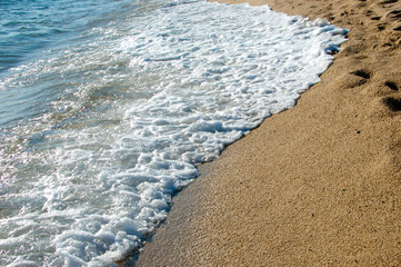 beautiful  small waves with foam of the sea on sandy beach at late afternoon, Greece at summer 