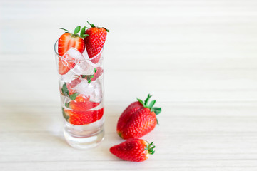 Strawberry in font of cocktail with ice isolated on white background with strawberry on top