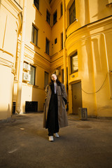 Young fashionable woman posing in the yard of city houses.