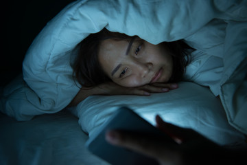 Asian woman play smartphone in the bed at night,Thailand people