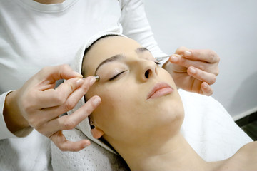 Fototapeta na wymiar beautician applying collagen treatment for area around the eyes with special sticks, procedure of regeneration and rejuvenation of the skin in beauty salon, close up