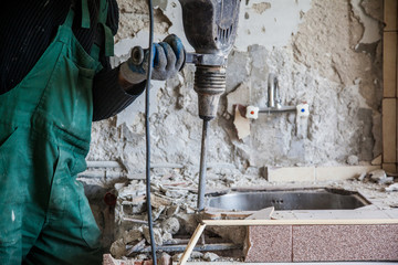 Repair and construction working indoors. Drill puncher breaks the old sink