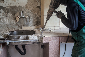 Repair and construction working indoors. Drill puncher breaks the old sink