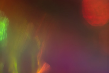 Blurred multicolor abstract lens flare on dark background. Defocused glow effect.