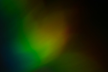 Blurred multicolor light reflection. Defocused lens flare glow. Dark abstract background.