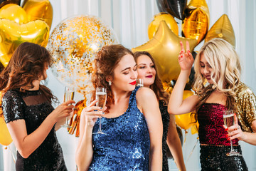 Fancy disco themed home party. Beautiful girls in sequin dresses hanging out, dancing, drinking...