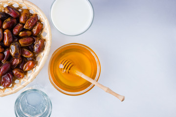 Dried dates, milk and honey on white background. Holy month of Ramadan, concept. Righteous Muslim lifestyle. Starvation. Dates in wooden basket and honey. Vegetarian food. Copy space