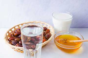 Dried dates, milk and honey on white background. Holy month of Ramadan, concept. Righteous Muslim lifestyle. Starvation. Dates in wooden basket and honey. Vegetarian food. Copy space