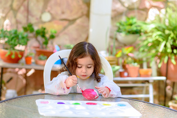 Portrait of little child painting, summer outdoor.Kid drawing on a stone.