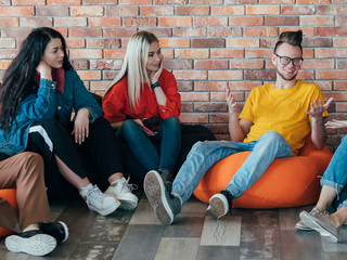 Modern work culture. Group of millennials relaxing on bean bags. Communication and discussion....